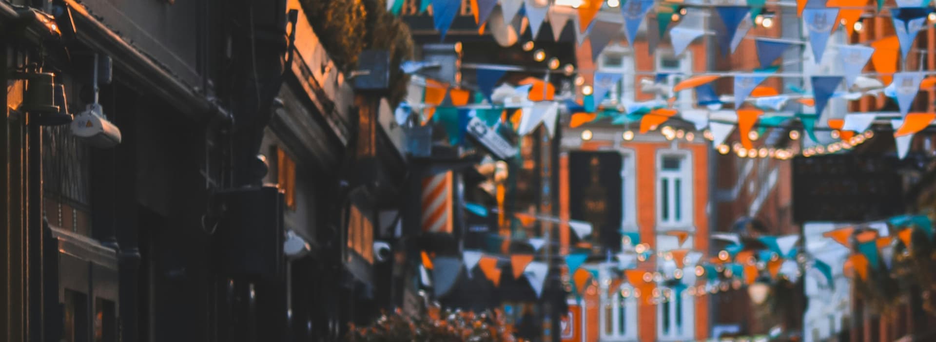 A vibrant street adorned with colorful bunting and flags hanging from the buildings, creating a festive atmosphere.